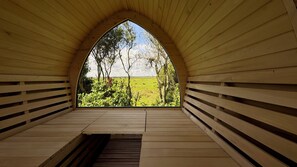 Una habitación con techo abovedado de madera, un banco y una ventana con vista a un campo verde.