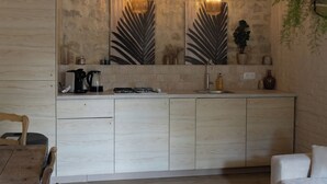 Una cocina moderna con encimera de madera, dos lámparas colgantes y un espejo grande con diseño de hojas.