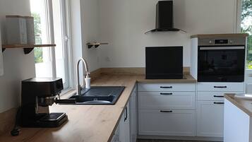 A modern kitchen with a coffee machine, a washing machine, a TV, and a built-in oven.