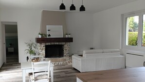 Una cocina moderna con chimenea de piedra, armarios blancos y encimera de madera.