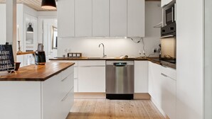 A modern kitchen with white cabinetry, a wooden countertop, a stainless steel dishwasher, and a built-in oven. - "Mark" - 1.2km from the sea by Interhome (Græsted)