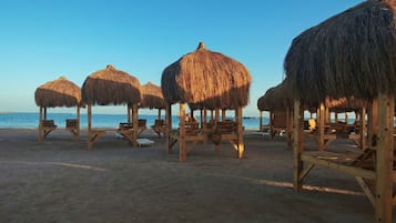 Een privéstrand, ligstoelen aan het strand, strandlakens, beachvolleybal