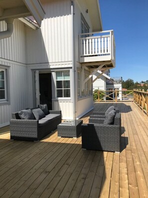A deck with outdoor furniture and a white building with a balcony. - Mollösund on the west coast near the sea, with beautiful views (Västra Götalands län)