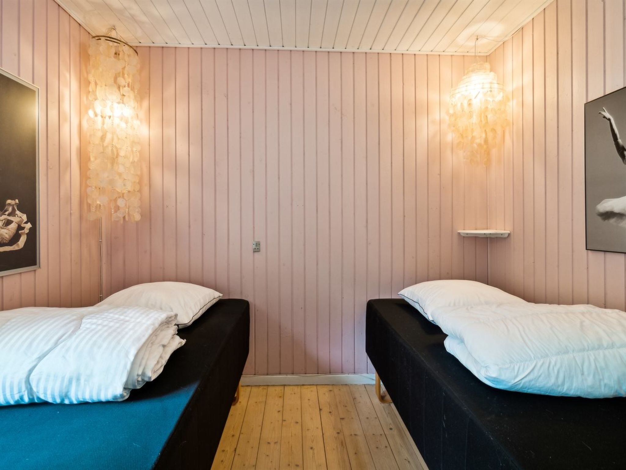 Ein Zimmer mit zwei Betten, Holzboden und Holzvertäfelung.