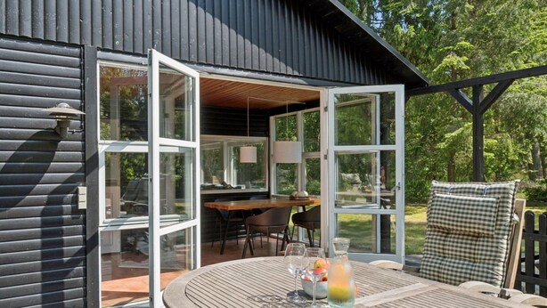 An open deck with a wooden table, chairs, and a glass of drink.