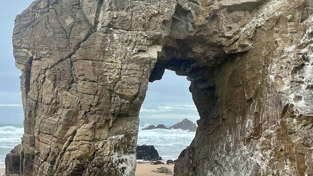 Eine natürliche Felsformation mit einer hohlen Öffnung an einem Sandstrand.
