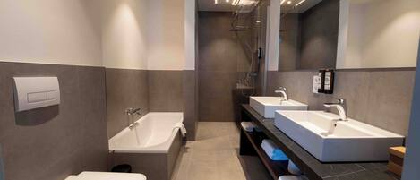 Un baño moderno con bañera, dos lavamanos y un inodoro.