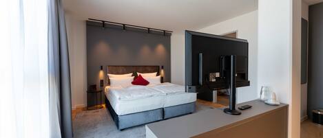Een moderne hotelkamer met een bed, nachtkastje, televisie en een bureau.