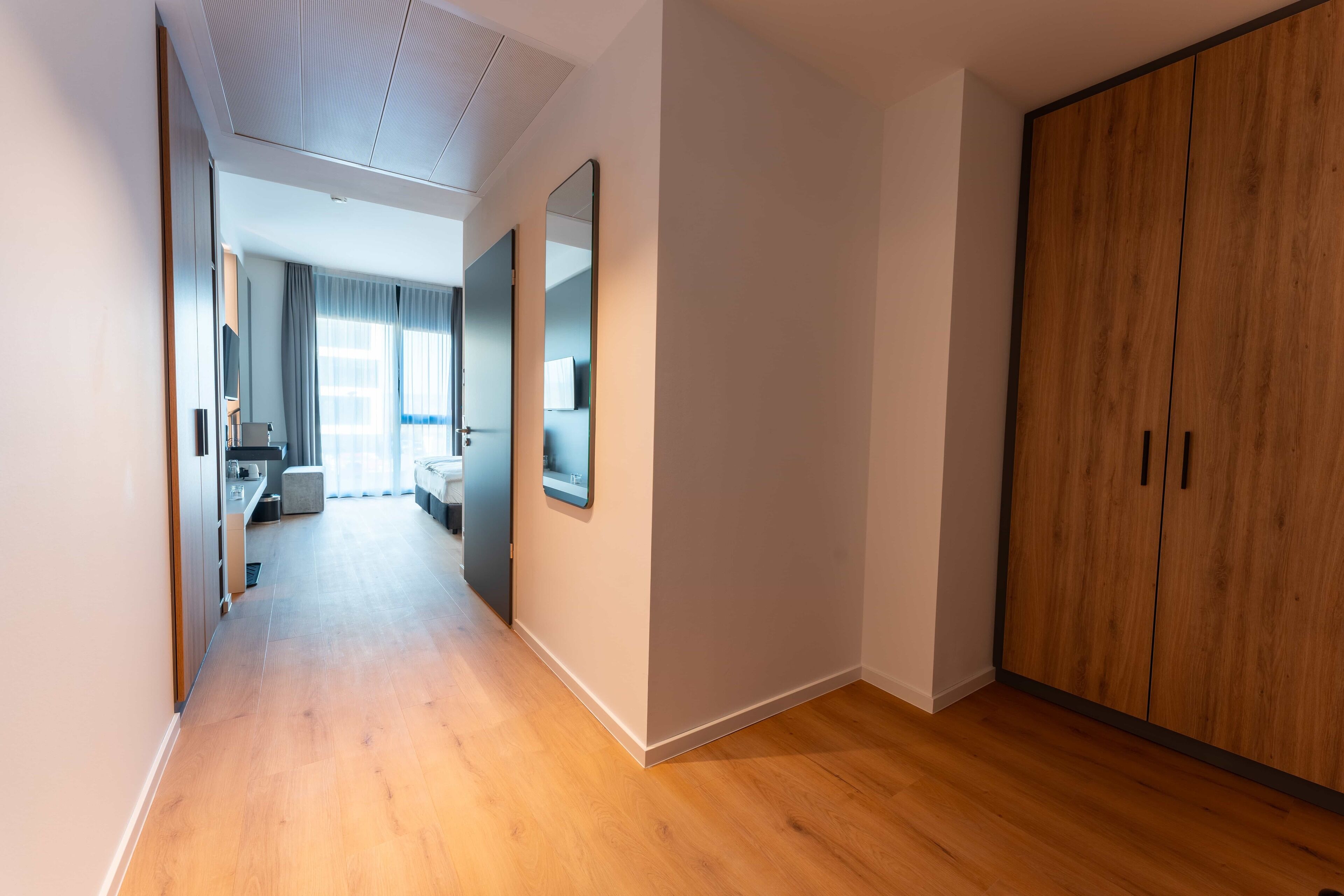 Ein Flur mit Holzboden, einem Kleiderschrank und einem Spiegel.