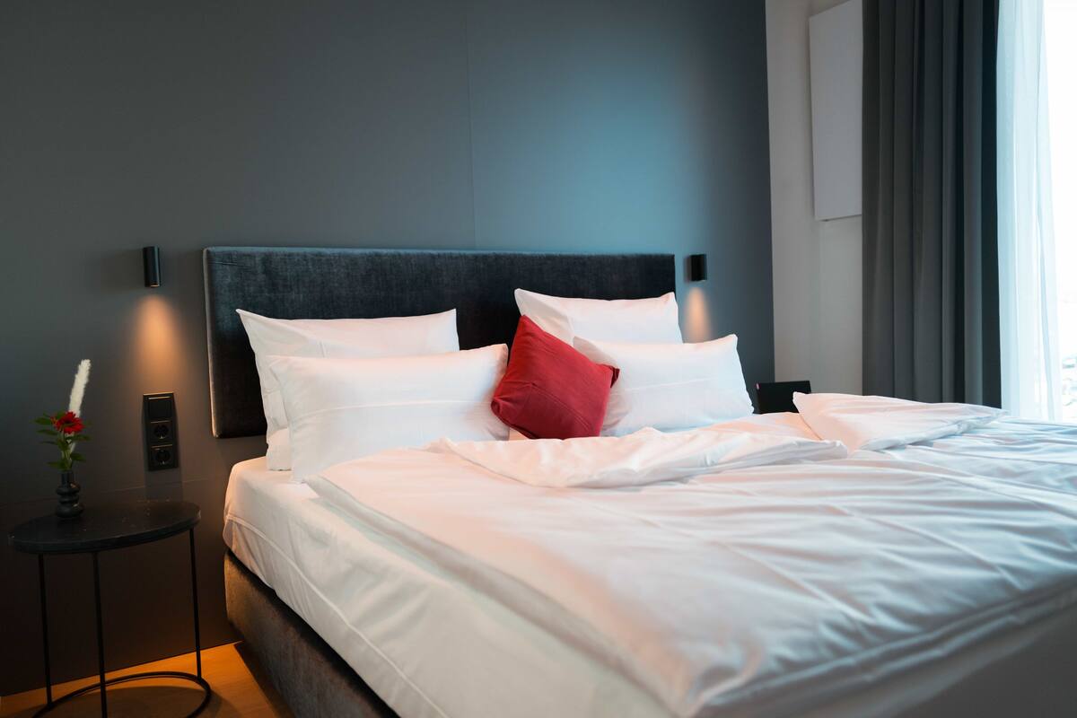 Een moderne hotelkamer met een groot bed, een nachtkastje en een wandlamp.