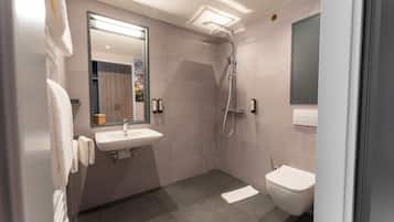 A modern bathroom with a sink, mirror, shower, and toilet.