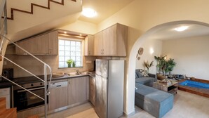 A modern kitchen with wooden cabinets, a stainless steel refrigerator, and a built-in oven. There is a staircase leading to an upper level. - Istros Villa III, Infinite Blue, Pool & Whirlpool (G37Q+HX Pithari, Greece)