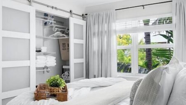 A bedroom with a bed, a window with curtains, a wardrobe, and a plant on the bed. - Cozy corner condo, just renovated,  pool views (Fort Lauderdale)