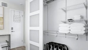 A white closet with shelves for folded clothes and a rack for hanging items. - Cozy corner condo, just renovated,  pool views (Fort Lauderdale)