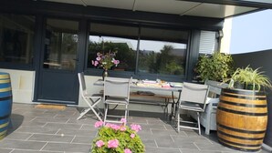 Une terrasse extérieure avec une table et des chaises, une plante en pot et un tonneau.