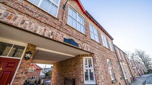 A brick building with a red door, a blue sign, and a covered entrance. - Corner Lodge - Central, refurbished & free parking (York)