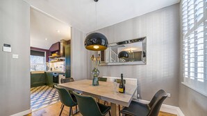 A dining area with a table, chairs, a mirror, and a pendant light. - Corner Lodge - Central, refurbished & free parking (York)