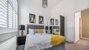 A modern bedroom with a large bed, bedside tables, a mirror, and artwork on the wall. - Corner Lodge - Central, refurbished & free parking (York)