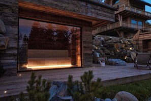 A modern log cabin with a large sliding glass door, a wooden deck, and a stone wall with seating. - Charming 3-bedroom country house with private SPA in tranquil Rzepiska (Rzepiska)