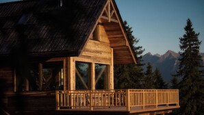 Una cabaña de madera con balcón, vista a un paisaje montañoso.
