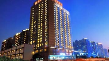 Een hoog gebouw met meerdere verdiepingen, vermoedelijk een hotel of appartementencomplex, met verlichte ramen die aangeven dat het bewoond is.