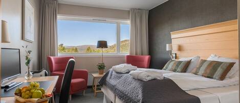 Una habitación de hotel con cama, escritorio, silla y vistas al exterior.