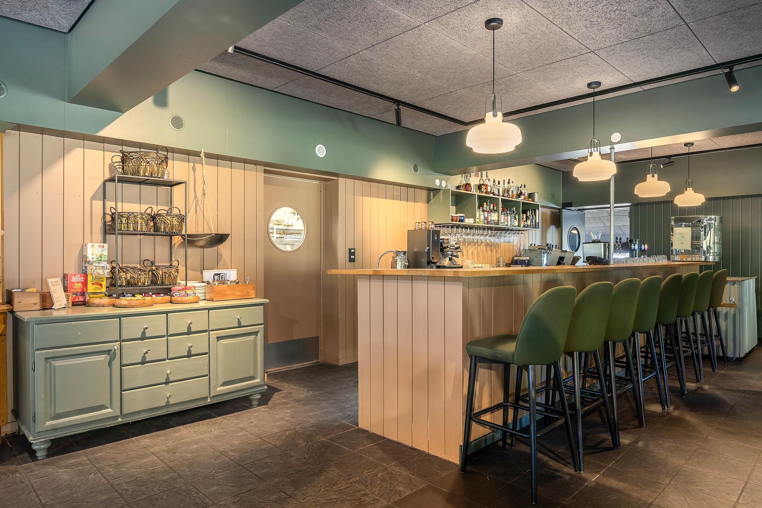 A bar area with a counter, stools, and a variety of bottles and glasses.