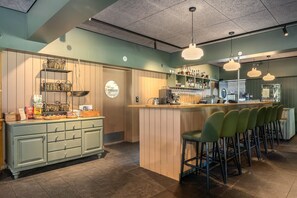 A bar area with a counter, stools, and a variety of bottles and glasses.