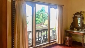 Una habitación con un ventanal grande, un escritorio de madera y un espejo.