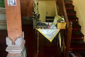 Uma escada com uma pequena mesa na base, um vaso de planta e uma placa.