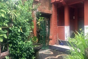 A courtyard with a brick building, a green gate, and a potted plant. - Puri Mandala Kaleran (Bali)