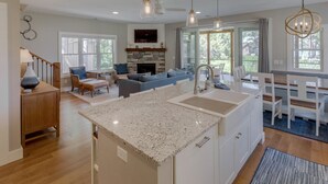 A modern kitchen with a granite countertop, a built-in oven, and a dining area with a white table and chairs. - Big Pine Beach House (Crosslake)