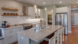 A modern kitchen with a granite countertop, stainless steel appliances, and pendant lighting. - Big Pine Beach House (Crosslake)