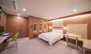 A hotel room with a bed, a desk with a chair, a vanity with a mirror, and a wardrobe. - Brown Dot Hotel Sangju (Sangju)
