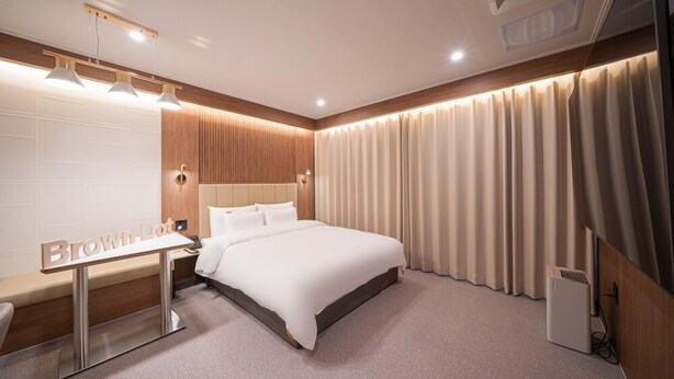 A modern hotel room with a large bed, a bedside table, and a desk with a mirror. - Brown Dot Hotel Sangju (Sangju)
