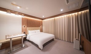 Une chambre d’hôtel moderne avec un grand lit, une table de chevet et un bureau avec un miroir.