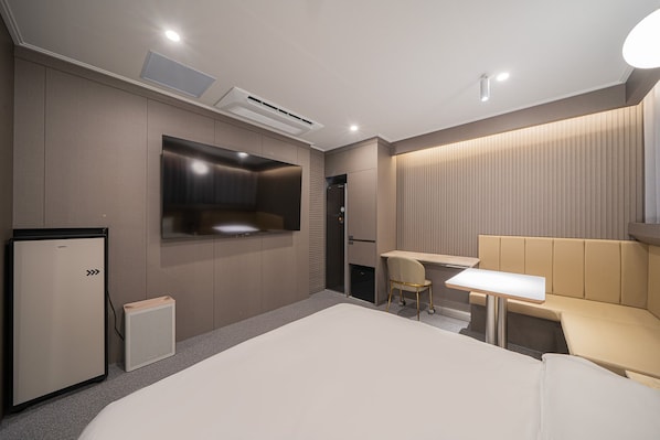 A modern hotel room with a large bed, a desk, a chair, a television, and a minibar. - Brown Dot Hotel Sangju (Sangju)