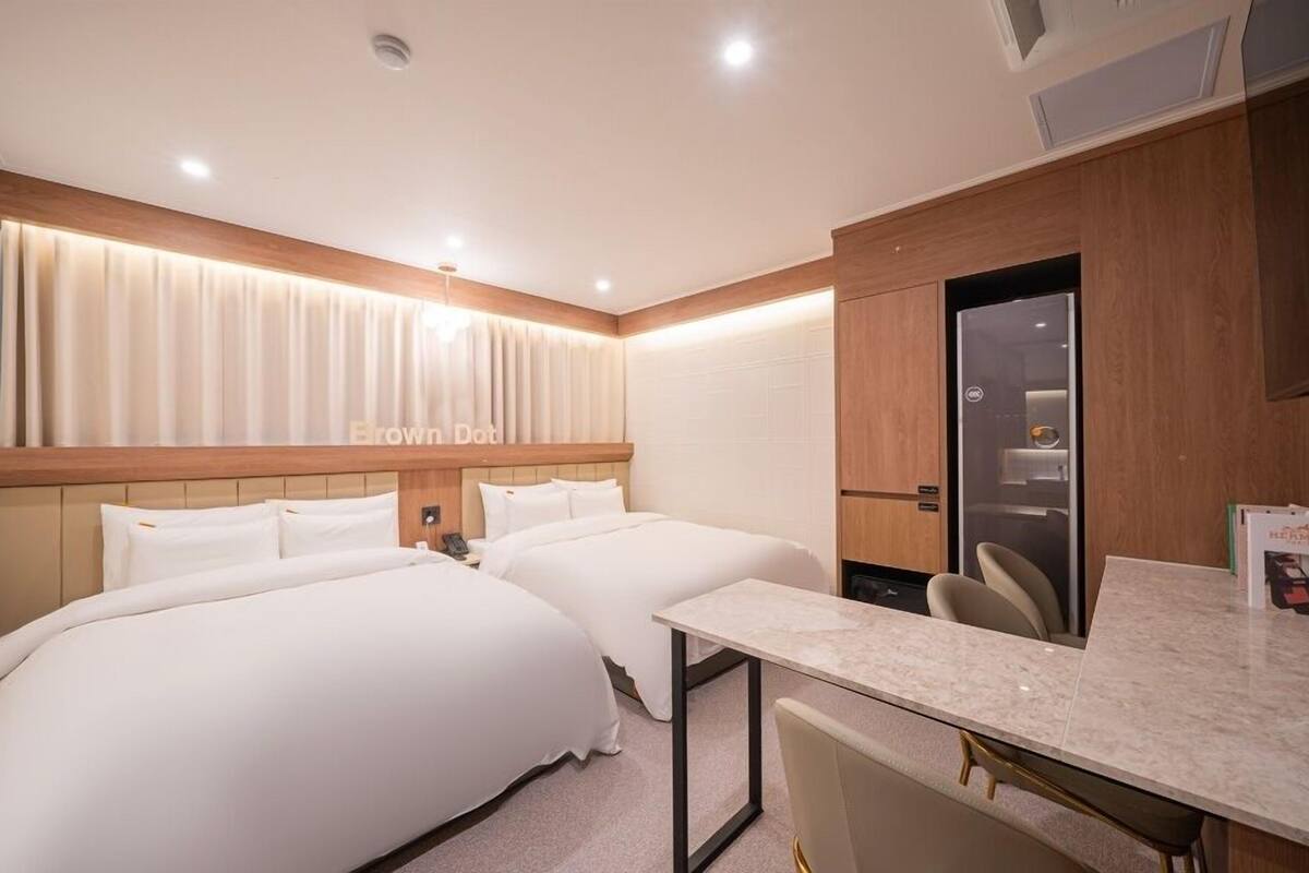 Ein Hotelzimmer mit zwei Betten, einem Schreibtisch und einer Minibar.