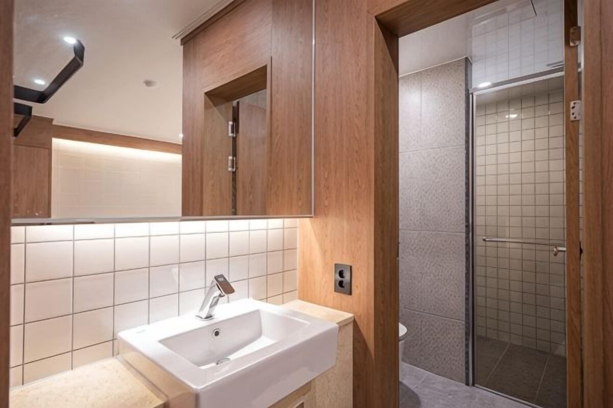 A bathroom with a sink, mirror, and shower.