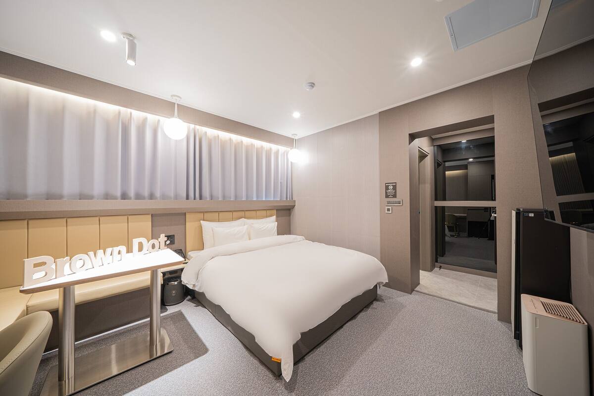 Ein modernes Hotelzimmer mit einem großen Bett, einem Schreibtisch und einem Kleiderschrank.