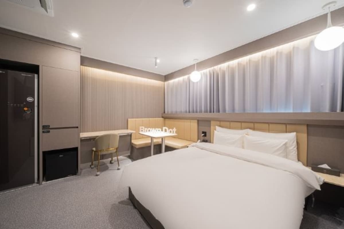 A modern hotel room with a large bed, a desk, and a seating area.