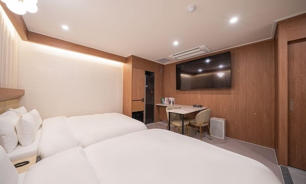 A hotel room with two beds, a desk, a chair, a flat-screen TV mounted on the wall, and a door. - Brown Dot Hotel Sangju (Sangju)