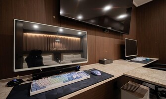 Ein modernes Hotelzimmer mit einem großen Flachbildfernseher, einem Schreibtisch mit Tastatur und Maus sowie einem Bett mit Kopfteil.