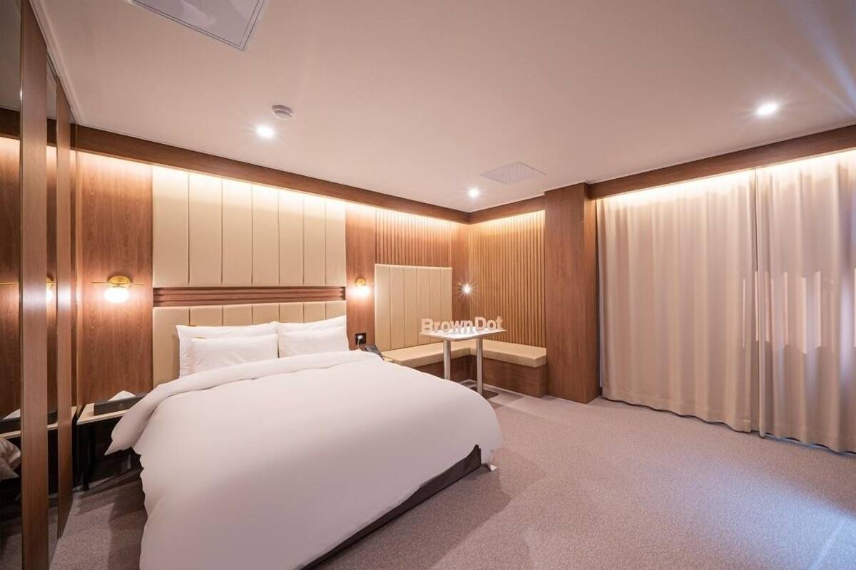 Ein modernes Hotelzimmer mit einem großen Bett, einem Schreibtisch und einem Spiegel.