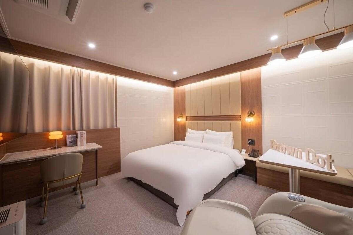 Ein Hotelzimmer mit Bett, Schreibtisch, Sessel, kleinem Tisch und einer Couch.