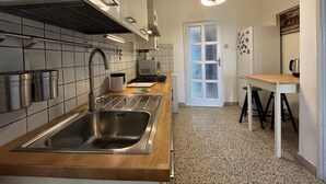 A modern kitchen with a stainless steel sink, a wooden countertop, a gas stove, and a white door with frosted glass panels. - Casa Tuttomondo in Pisa (Pisa)