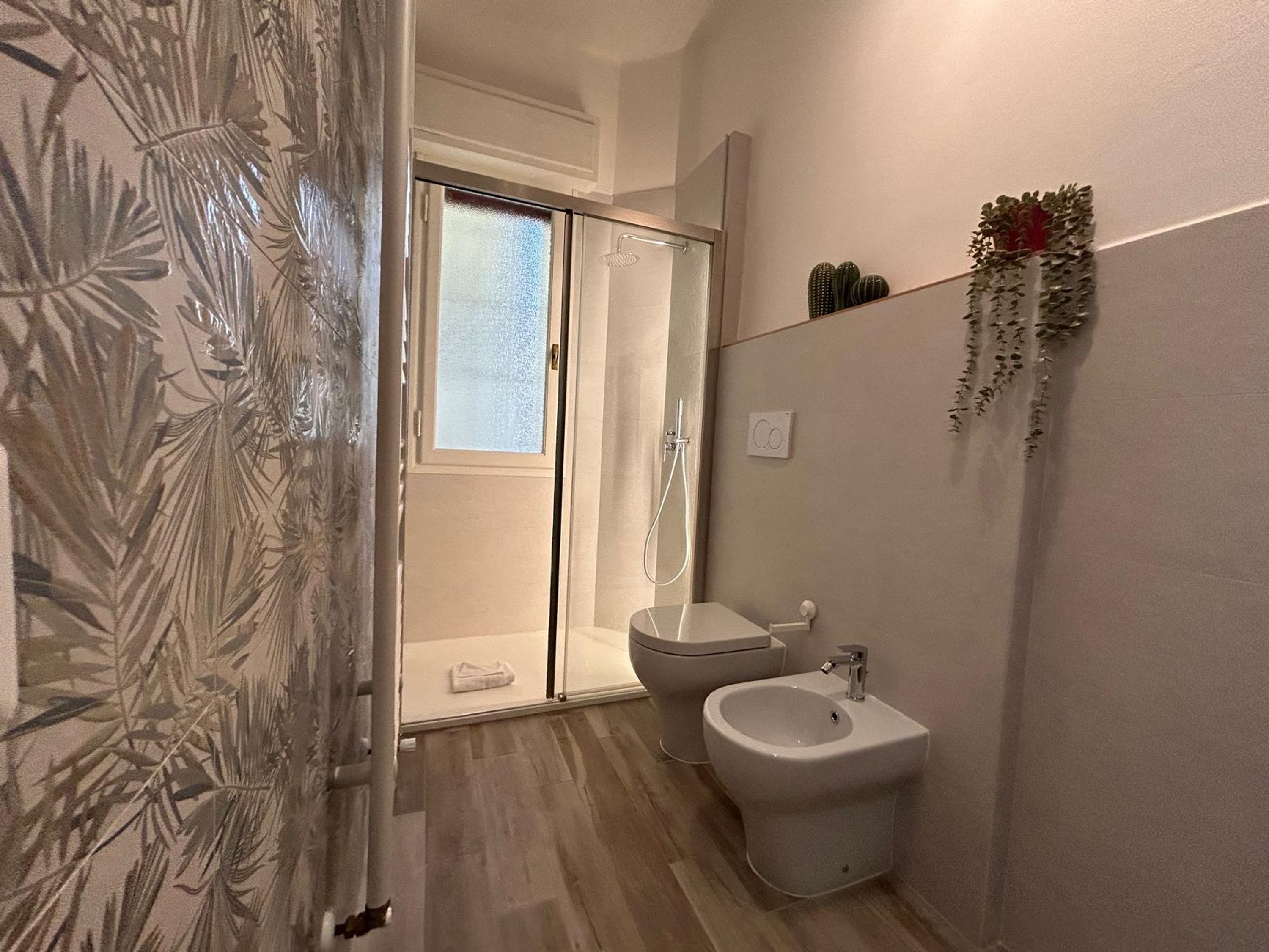 Un baño con ducha, inodoro, bidé y un espejo.