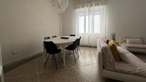 A dining area with a round table and chairs, a chandelier, and a sofa with patterned cushions. - Casa Tuttomondo in Pisa (Pisa)