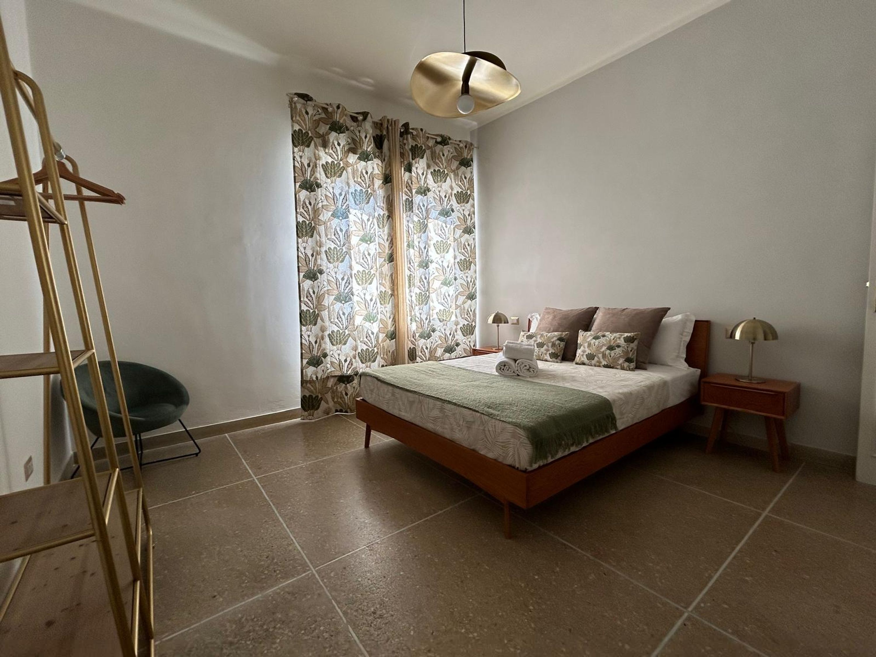 A bedroom with a bed, a nightstand, a lamp, a chair, and a ladder.