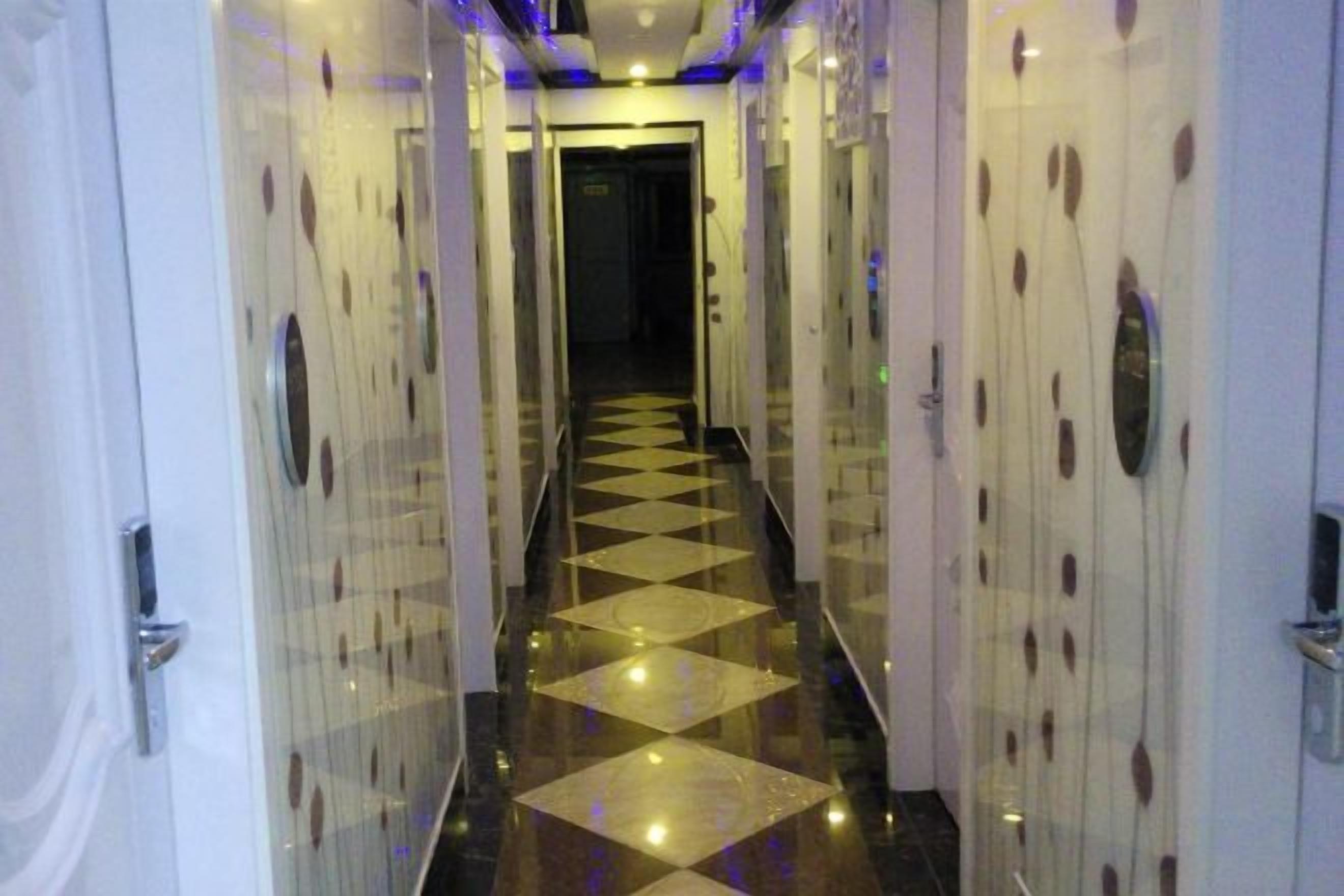 A hotel corridor with mirrored walls and a checkered floor.